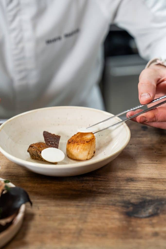 photo culinaire main qui dresse le plat