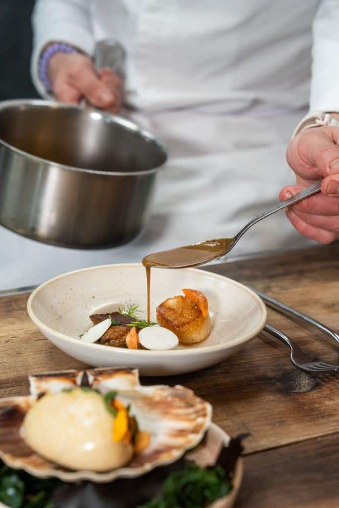 photo culinaire geste cuisine main qui ajoute de la sauce