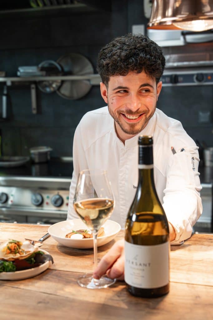 portrait de Quentin Maufrais avec un verre de vin et une bouteille de Versant Viognier des Vignobles de Foncalieu