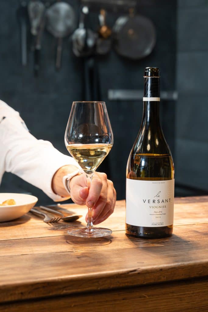 photo d'un verre de vin avec une bouteille de vin blanc le versant Viogner des vignobles de Foncalieu