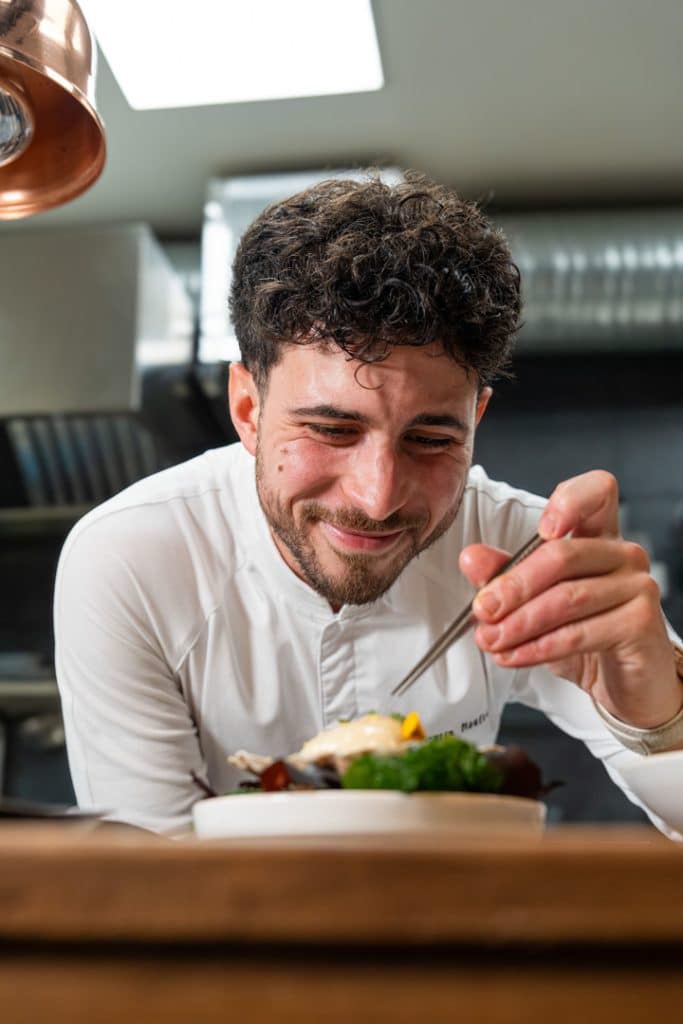 photo culinaire du chef Quentin Maufrais souriant en train de dresser un plat