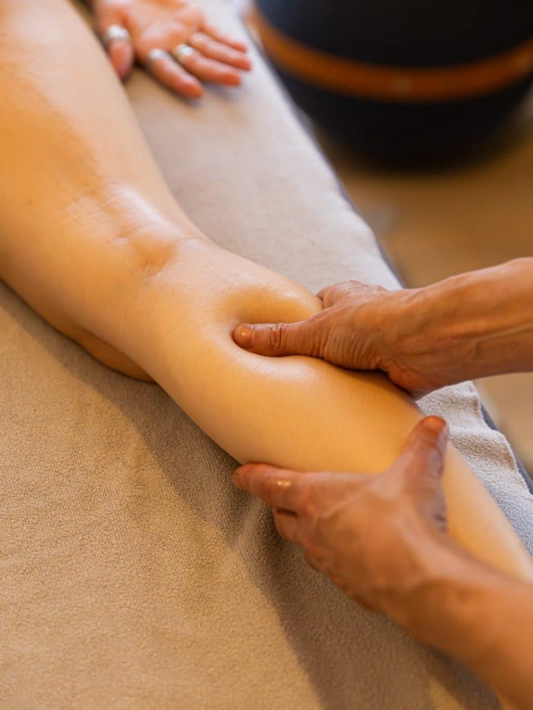 photographie de mains en train de masser une jambe